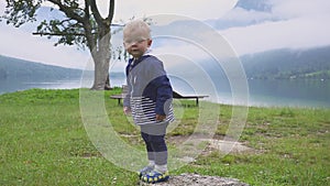 The little boy walks near the mountain lake. Running and frolicking in nature. Slow motion