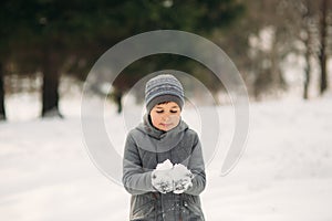 A little boy walks in the park in the winter weather, play snowballs and rejoiced. Waiting for Christmas mood