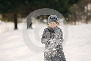 A little boy walks in the park in the winter weather, play snowballs and rejoiced. Waiting for Christmas mood