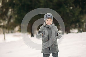 A little boy walks in the park in the winter weather, play snowballs and rejoiced. Waiting for Christmas mood