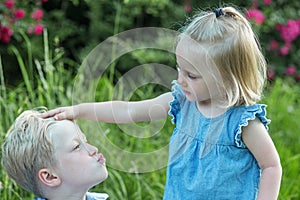 Little boy wants to kiss sister. Children play and fool around in nature