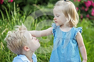 Little boy wants to kiss sister. Children play and fool around in nature