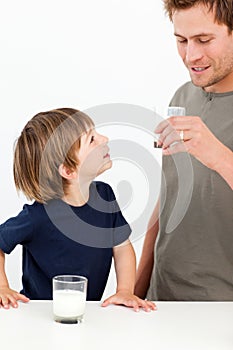Little boy watching his father drinking milk