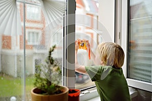 Little boy watching the rain outside at opened window and taking photo. Bad weather - wind and downpour. Inquisitive child explore