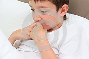 A little boy watching video on a smartphone at home in bed and he is wondered and scared, fear expression on a face of a