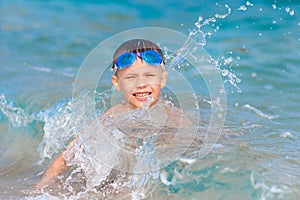 Little boy with water glasses swims in sea