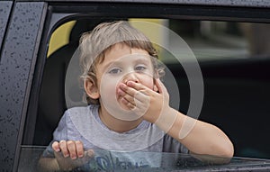 Little boy waving through the car window