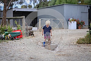 Little boy wearing gum boots jumping and splashing in puddle