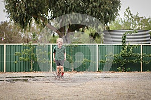 Little boy wearing gum boots jumping and splashing in puddle