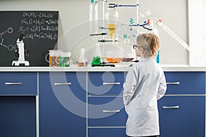 Little boy wearing lab coat in science laboratory