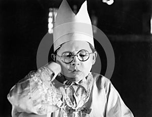Little boy wearing a paper crown sitting with his eyes closed