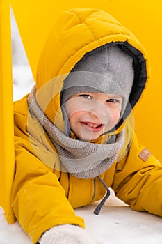 Little boy wearing scarf and hood in winter snow