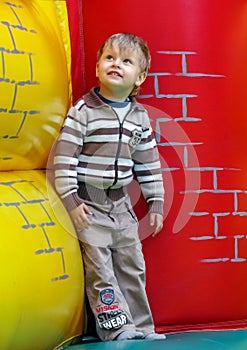 A little boy wearing striped sweater jumps on a trampoline.