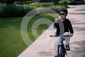 A little boy wearing sunglasses is riding a bicycle