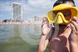 Little boy wearing yellow diving mask and swimming goggles on the beach