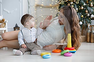 Mom with little son playing with colored blocks near the Christmas tree