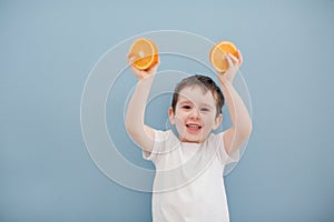 Little boy in white t-shirt holds two orange slices