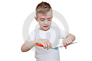 Little boy in white t-shirt squeezes toothpaste on brush. Health care, hygiene and childhood concept. Caries prevention