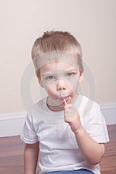 Little boy in white tshirt sucking lollipop in his