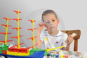 Little boy - woodcraft ship painting, thinking