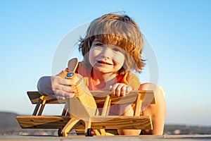 Little boy with wooden plane, boy wants to become pilot and astronaut. Happy child play with toy airplane. Kids pilot