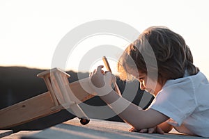 Little boy with wooden plane, boy wants to become pilot and astronaut. Happy child play with toy airplane. Kids pilot