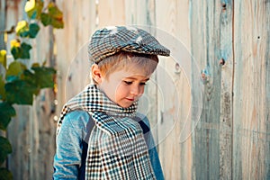 Little boy on a wooden wall background. Humble shy child. Melancholy. Romance. Melancholic mood.