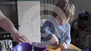 A little boy works in the kitchen, he cuts a pumpkin