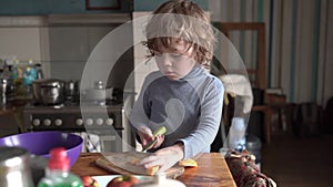 A little boy works in the kitchen, he cuts a pumpkin