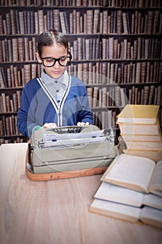 Little boy writer on desk with typewriter in library