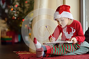 Little boy writing the letter to Santa. Child dreams of a gift that he can receive