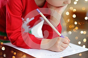 Little boy writing the letter to Santa. Child dreams of a gift that he can receive. Magic mail of Santa Claus