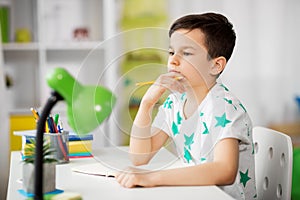 Little boy writing to notebook at home