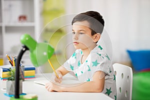 Little boy writing to notebook at home