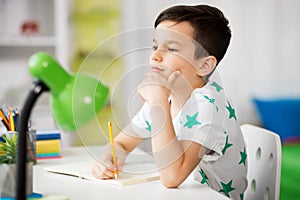 Little boy writing to notebook at home