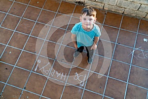 Little boy wrote on the road, Be Happy. View from above. Cute Boy drawing with a chalk.