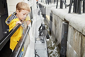 Little boy in yellow jacket on pleasure boat deck photo