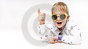 A little boy in yellow sunglasses and blue children`s smart watches.
