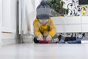 A little boy in a yellow sweater and hat is counting money and studying heating bills, near a heater with a thermostat