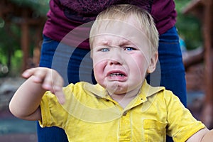 Little boy in a yellow T-shirt is badly upset and crying. Tears on her cheek