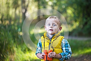 The little boy young researcher looks up and exploring with binoculars environment