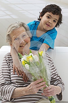 Little boying offering flower to his grandmother