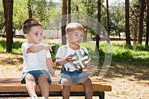 Little boys: African American and caucasian with soccer ball in park on nature at summer.