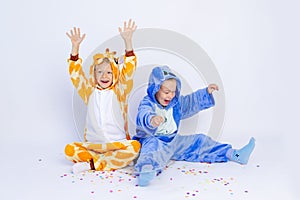 Little boys brothers in fun bright costumes indulge and have fun on a white isolated background with confetti, children`s birthda