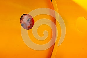 Little boys face in a playground equipment plastic tube tunnel