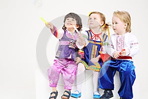 Little boys and girl in folk costumes sits with