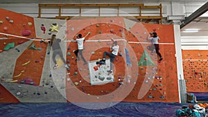 Little boys and girls 4 people climb up the indoor climbing wall