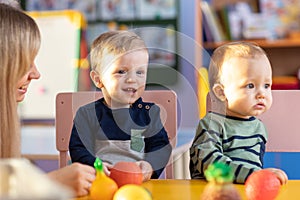 Little boys playing indoors at home or kindergarten. Adorable children with educator play plastic vegetables and fruits. photo
