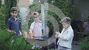 Little boys plays with fire in the barbecue grill