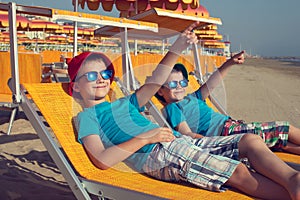 Little boys relax on deckchair showing away